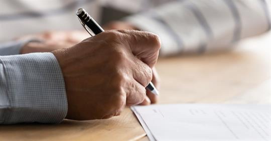 elderly person signing a document